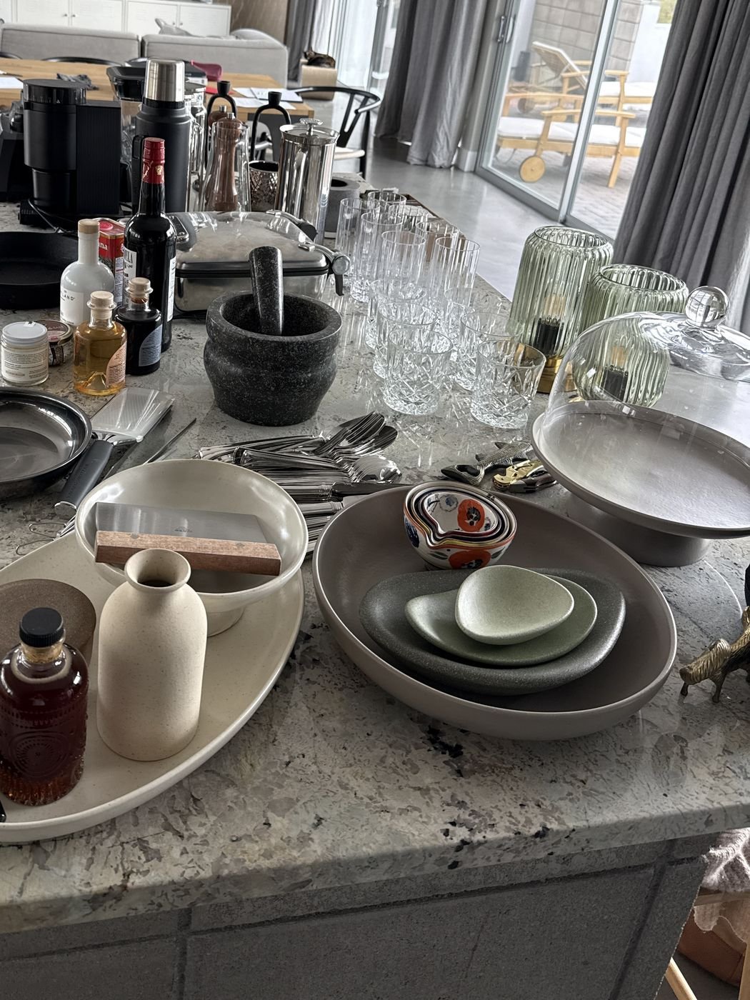 A kitchen island with a mortar and pestle, glassware and serving dishes