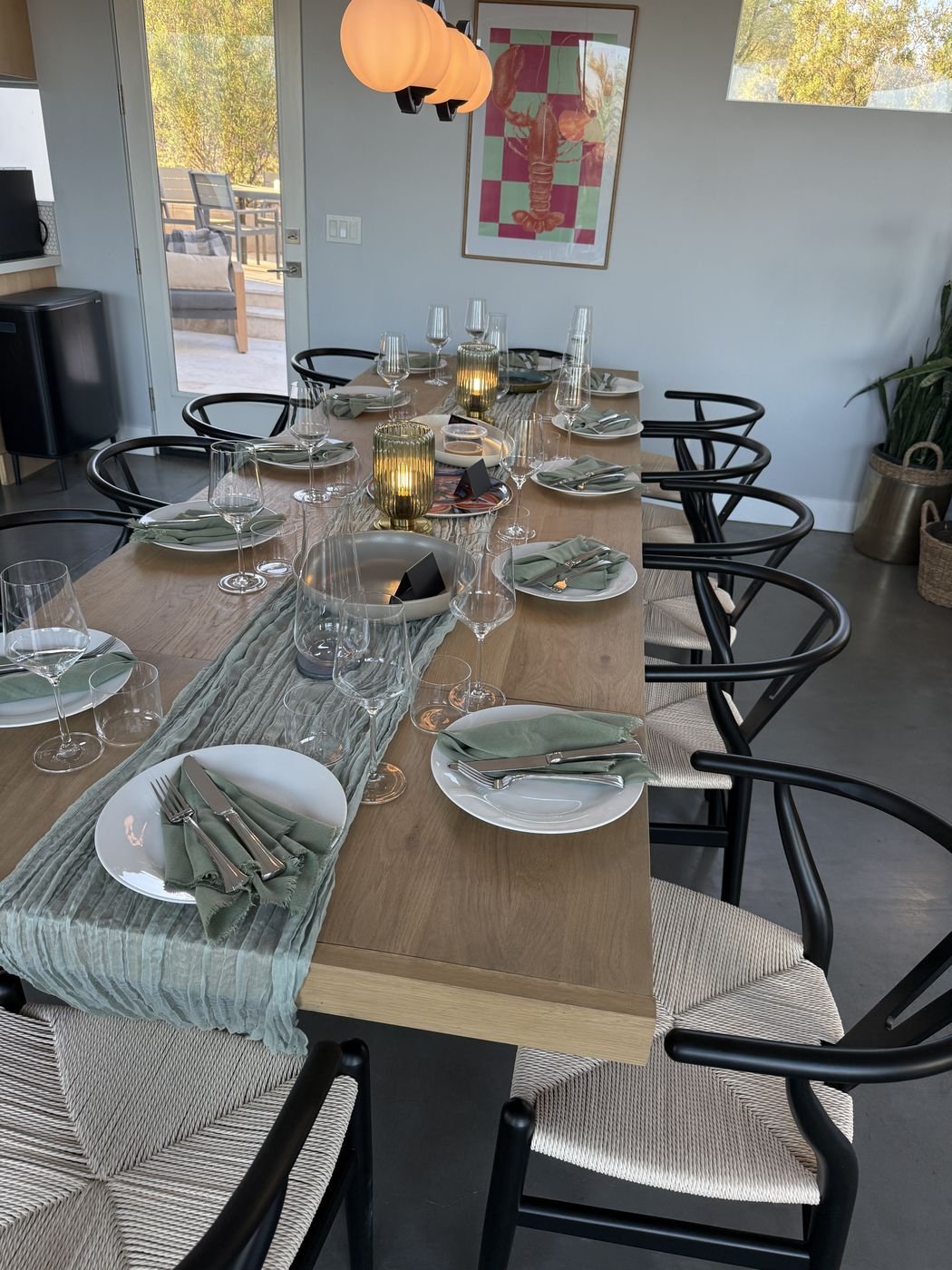 A long table set with linen, candles and glassware, ready for dinner guests