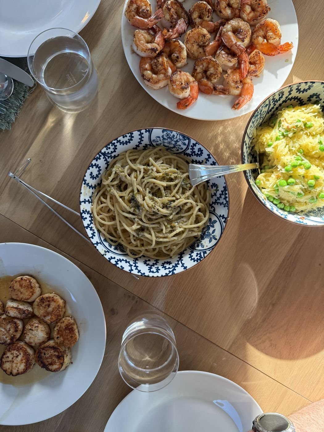 A sunlit table spread of grilled shrimp, seared scallops and pasta
